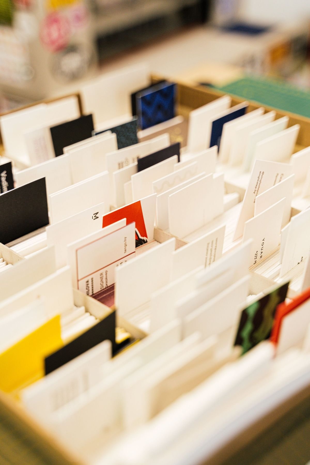 A box of printed business cards in different colours and paper finishes