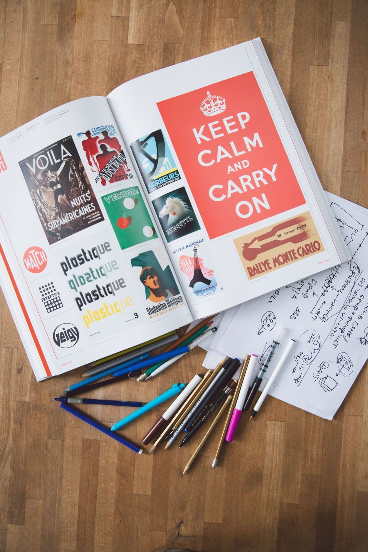A design book open beside pencils and hand-drawn sketches, gathering ideas for a project