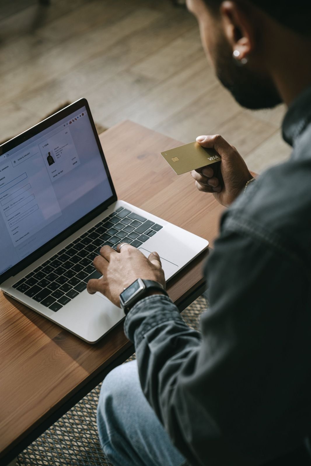 Someone holding a payment card while checking out on a laptop
